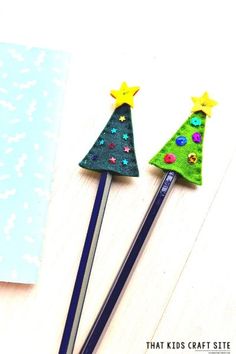 two felt christmas trees sitting on top of pencils