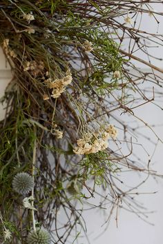 the branches and flowers are hanging on the wall in front of the door, which is covered with moss