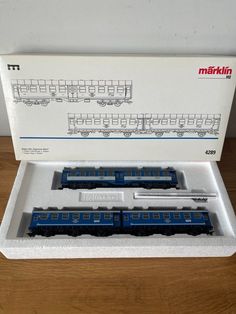 two blue and white train cars in a box