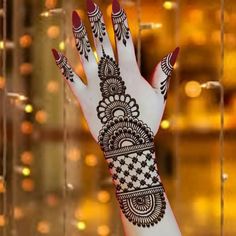 a woman's hand with henna on it and some lights in the background