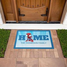 a door mat with the words home and spiderman on it in front of a house