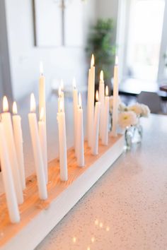 many white candles are lined up on a table