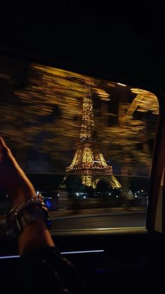 the eiffel tower is lit up at night as seen from inside a car