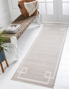 a white rug on the floor next to a basket and potted plant in front of a door