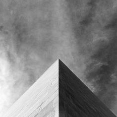 a black and white photo of the top of a building with clouds in the background