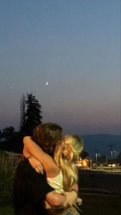 a man and woman hug each other in front of the moon