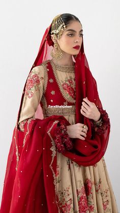 a woman in a red and beige dress with flowers on her head wearing a veil