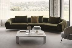 a living room filled with furniture next to a large glass window covered in white curtains