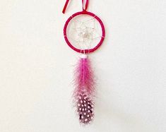 a pink and white dream catcher hanging on a wall