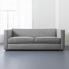 a gray couch sitting on top of a blue floor next to a white brick wall