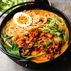 a bowl filled with noodles, meat and an egg