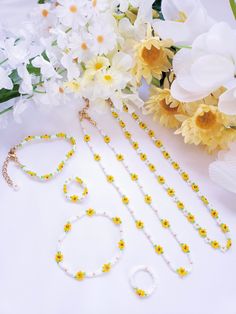 the necklace and bracelets are on display next to some white flowers, including daffodils