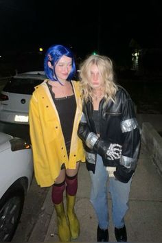 two women standing next to each other in front of a car