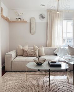 a living room filled with furniture and a white couch in front of a large window