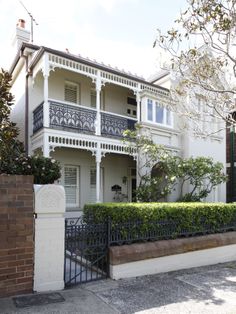 an ornate white house with black iron fence