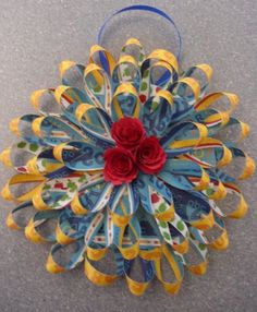 an ornament made out of strips of paper with flowers in the center and blue ribbon on top