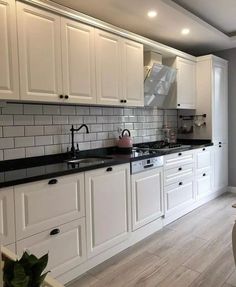 a kitchen with white cabinets and black counter tops