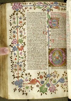 an open book with ornate designs and writing on the pages is being held by a person's hand