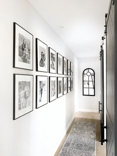 a hallway with black and white pictures on the wall next to an open front door