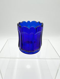 a blue glass vase sitting on top of a clear shelf