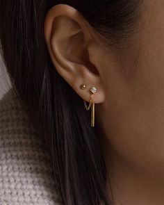 a close up of a person wearing a pair of ear piercings with gold posts