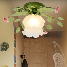 a bath room with a toilet and a flowery light hanging from the ceiling above it