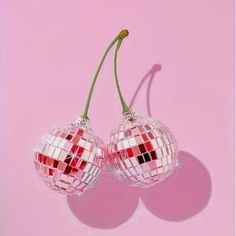 two red and white ornaments hanging from a pink wall