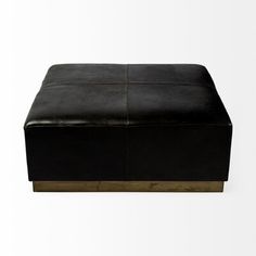 a black leather ottoman sitting on top of a white floor