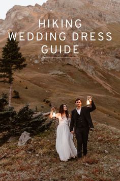 a bride and groom walking on top of a mountain holding candles in their hands with the words hiking wedding dress guide