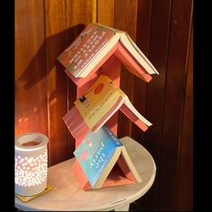 a stack of books sitting on top of a table next to a cup and candle