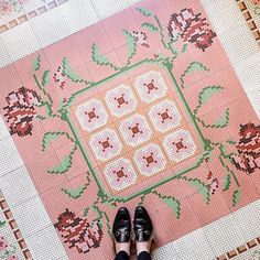 a person standing in front of a pink rug with flowers and leaves on the floor