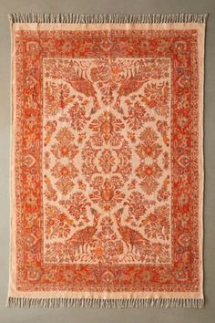 an orange and white rug with fringes hanging on the wall in front of it