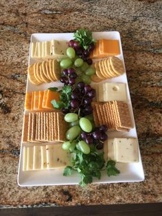 grapes, cheese and crackers arranged on a plate