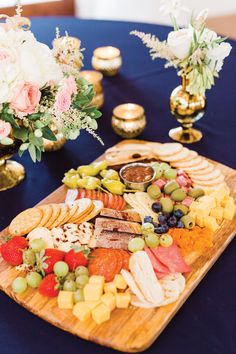 a wooden platter filled with cheese, crackers and fruit