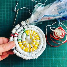 a person is holding an object made out of yarn and other crafting supplies on a table