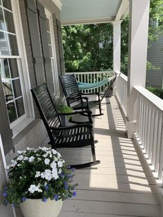 three rocking chairs on the front porch of a house with flowers growing out of them