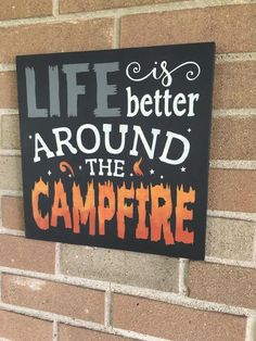 a sign on the side of a brick building that says life is better around the campfire