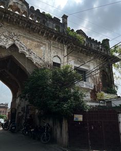 an old building with vines growing out of the roof and on top of it is a motorcycle parked in front