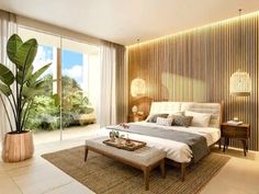 a bedroom with a large bed sitting next to a tall plant on top of a wooden table