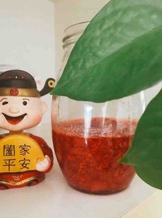 a jar filled with red liquid next to a small figurine holding a sign