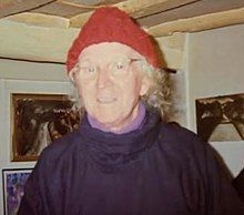 an older woman wearing a red hat and black shirt in a room with pictures on the wall