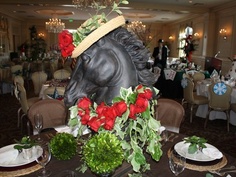 there is a horse statue on the table with roses in it and place settings around it