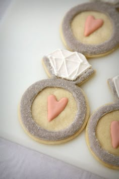 some cookies with pink and white icing are on a table next to each other