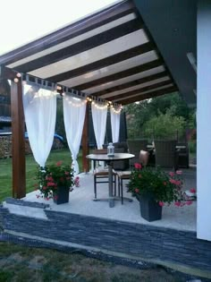 a covered patio with potted plants and flowers on the table under an awning