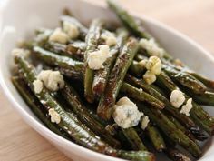 a white bowl filled with green beans covered in blue cheese