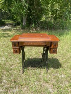 an old sewing table in the middle of some grass