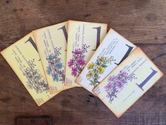 five envelopes with flowers on them sitting on a wooden table