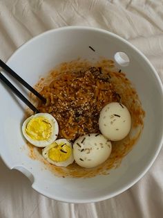 an image of eggs and rice in a bowl with chopsticks on the side