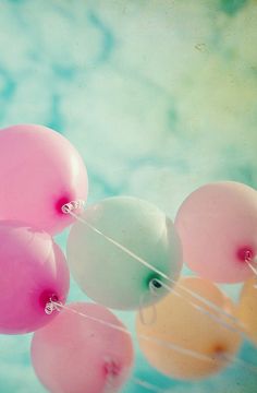 some pink and white balloons floating in the air