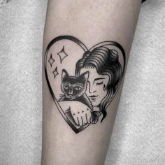 a woman holding a cat in her arm with a heart shaped tattoo on the forearm